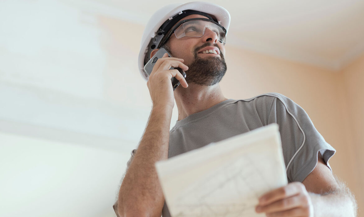 Agence développement solutions digitales constructeur de maison au téléphone avec plan dans les mains