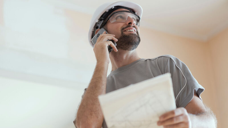 Agence développement solutions digitales constructeur de maison au téléphone avec plan dans les mains