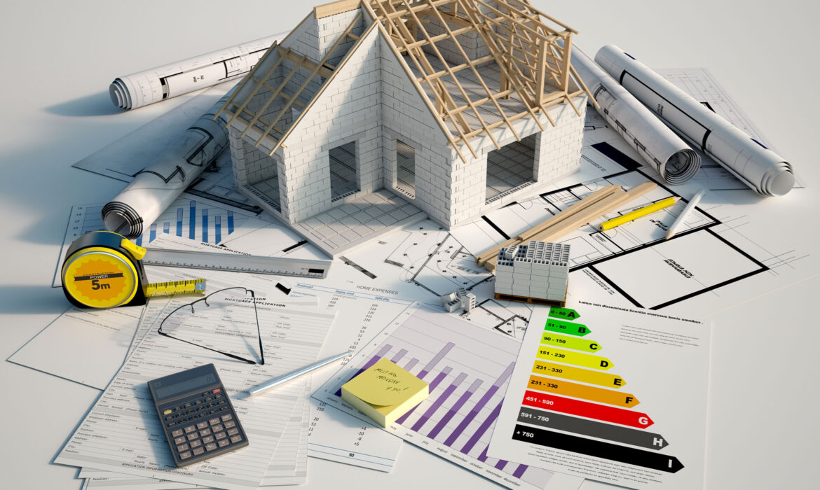 Maquette de maison posée sur un bureau avec des plans, une calculette, un dpi, un mètre, ...