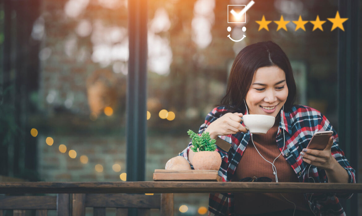 Jeune femme devant son téléphone portable en train de boire un café, des étoiles de satisfaction client au dessus d'elle