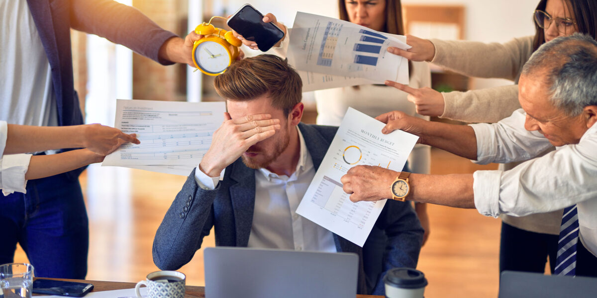 Homme débordée de tâches quotidiennes avec groupe autour de lui, burn out